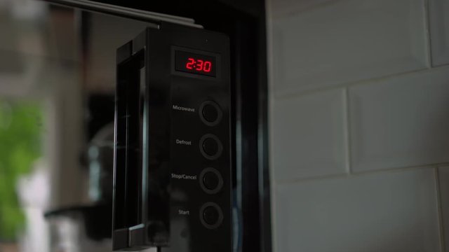 Microwave timer set for two minutes thirty seconds by male hand count down