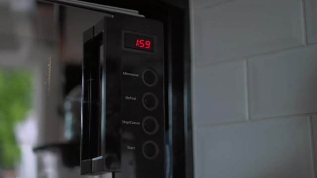 Microwave timer set by male hand for two minutes count down