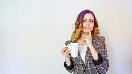 girl stands with a cup of coffee and dreams. girl in a checkered jacket drinks coffee