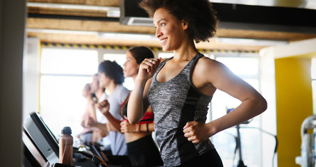 Young people running on a treadmill in health club.