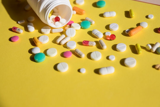 Pills spilling out of pill bottle isolated on yellow background.tablets and capsules.Painful old age. Health care of older people.suicide.medicine and pharmacy drugs.Copy space