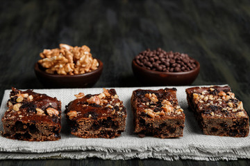 pieces of chocolate brownie and walnuts next to walnuts and chocolate in clay pots in the foreground