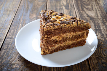 Chocolate cake with nut cream on a wooden table. A piece of cake on a plate