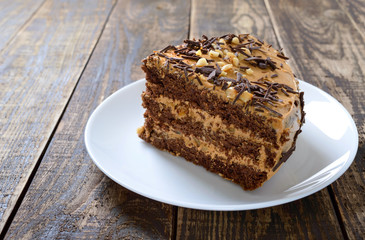 Chocolate cake with nut cream on a wooden table. A piece of cake on a plate