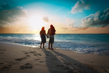 happy family with two kids walk on sunset beach