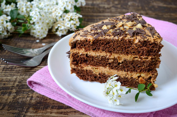 Chocolate cake with nut cream on a wooden table. A piece of cake on a plate . Close up
