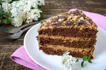 Chocolate cake with nut cream on a wooden table. A piece of cake on a plate . Close up