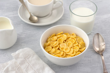 Sweet crunchy cornflakes with milk on a gray textured background. Fast tasty breakfast, top view, horizontal