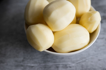 peeled raw potatoes in white plate