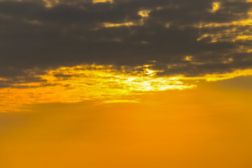 The sun is hidden behind the clouds in orange sky