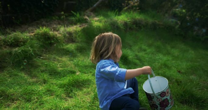 Little preschooler boy with bucket in garden surorunded by bubbles