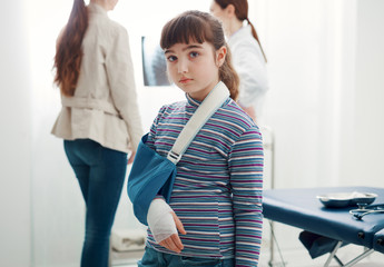 Cute girl with arm brace in the doctor's office