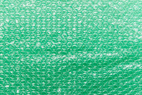 Green bubble wrap air filled transparent packaging foil placed on green backgound.