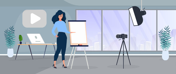 The girl is giving a presentation in front of the camera. The teacher conducts a lesson online. The concept of blogs, online training and conferences. Camera on a tripod, softbox.
