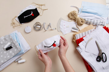 Sewing black & white funny anti-virus mask. Homemade mask with smile. DIY face mask for safety at pandemic or quarantine. Zero waste handmade cotton natural mask against infection. Smile & stay safe