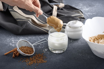 process of making Dalgona coffee, Korean drink on gray kitchen table, hand puts foam in glass of milk
