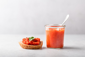 Ajvar sauce in a glass on a light background, minimalism style.