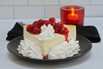 A plate with New York style cheesecake garnished with whipped cream and cherries.
