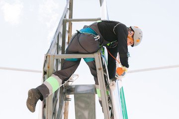 Industrial climber in helmet and overall working on height. Risky job. Bottom view