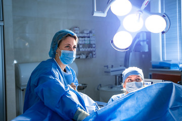 Team of surgeons performing operation in bright modern surgery room. Operating theatre. Modern...