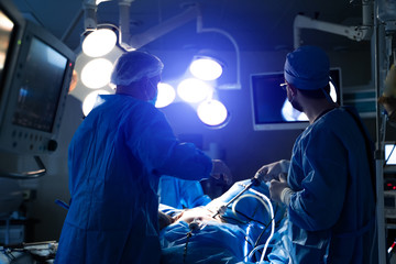 Operating room with surgery in progress. Medical team performing surgical operation in bright...