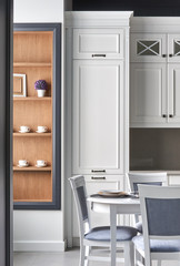 Fototapeta premium Italian kitchen in classic style with white painted facades with a dining table for 4 people