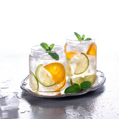 Orange cocktail with mint and lime. Cold refreshing drink or beverage with ice.