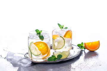 Cold drinks with ice and mint. Orange cocktail on gray concrete background