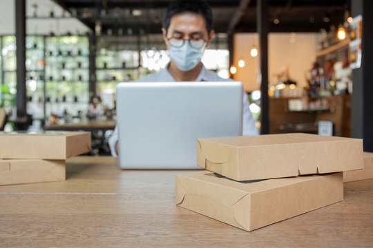 Selected ocus parcel on table with man wearing medical mask work on laptop.