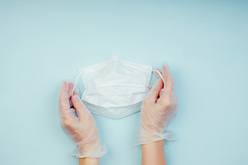 Medical mask in the hands of a doctor on blue background, flatlay top view
