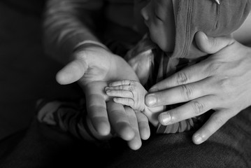 Father and baby hands. Baby’s hand in dad’s hand, black and white photo.
