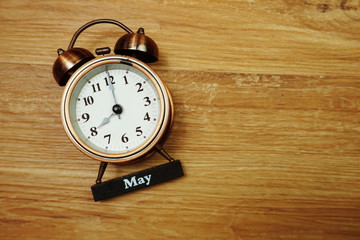 May and alarm clock with space copy on wooden background