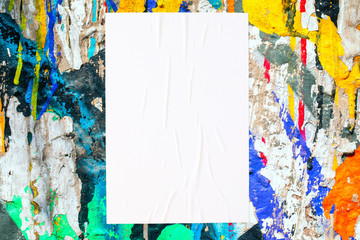 Closeup of colorful messy painted urban wall texture with wrinkled glued poster template . Modern...