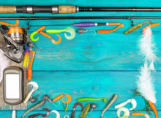 Fishing rod, tackles, reel and fishing baits, reel on wooden board background. Empty space for text