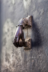 Antique bronze door knocker in shape of a hand in old house in Valencia, Spain