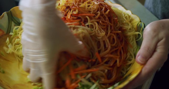 Close up of mixing Korean chili paste (gochu gang) with Korean chewy noodles (jjolmyeon) in a large bowl to create Korean Spicy Chew Noodles.
