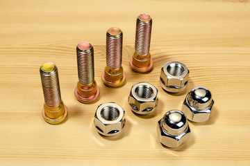 Auto parts. Wheel nut and stud on a wooden table