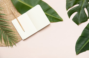 Fltlay style concept with text place at the center and the border of notebook, pencil with round wicker stand and tropical palm leaves on pink background.
