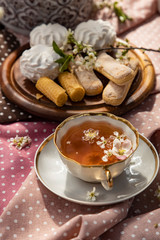White porcelain tea cup with flowers on a white saucer and sweets on a summer table