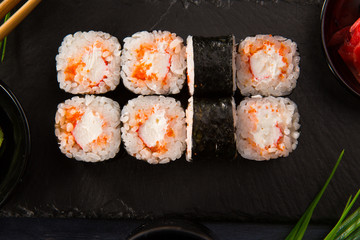 Set of sushi rolls with wasabi and ginger on a black background. Japanese oriental cuisine