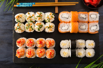 Set of sushi rolls with wasabi and ginger on a black background. Japanese oriental cuisine