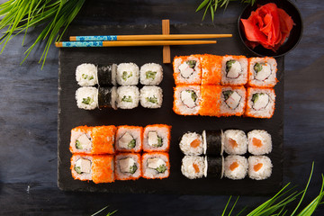 Set of sushi rolls with wasabi and ginger on a black background. Japanese oriental cuisine
