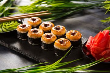 Set of baked sushi rolls with wasabi and ginger on a black background. Japanese oriental cuisine