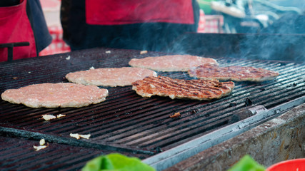  Beef burgers cooking on griddle plate. Fry on an open fire on the grill.