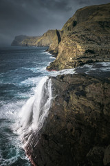 Fototapeta na wymiar Waterfall and sea cliffs of Faroe Islands.