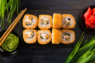 Set of fried sushi rolls with wasabi and ginger on a black background. Japanese oriental cuisine