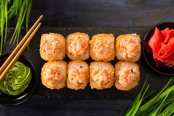 Set of fried sushi rolls with wasabi and ginger on a black background. Japanese oriental cuisine