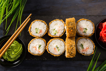 Set of fried sushi rolls with wasabi and ginger on a black background. Japanese oriental cuisine