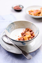 Healthy breakfast yogurt bowl with granola and caramelized bananas and nuts on grey concrete background. Selective focus