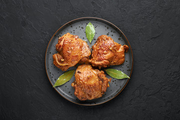 Filipino Chicken Adobo on dark gray plate on black slate backdrop. Chicken Adobo is Filipino cuisine dish of braised chicken thighs, soy sauce, vinegar, black pepper and bay leaves. Filipino food